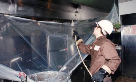 Rimozione grassi da cappa industriale Operatore durante pulizia interna cappa ristorante
